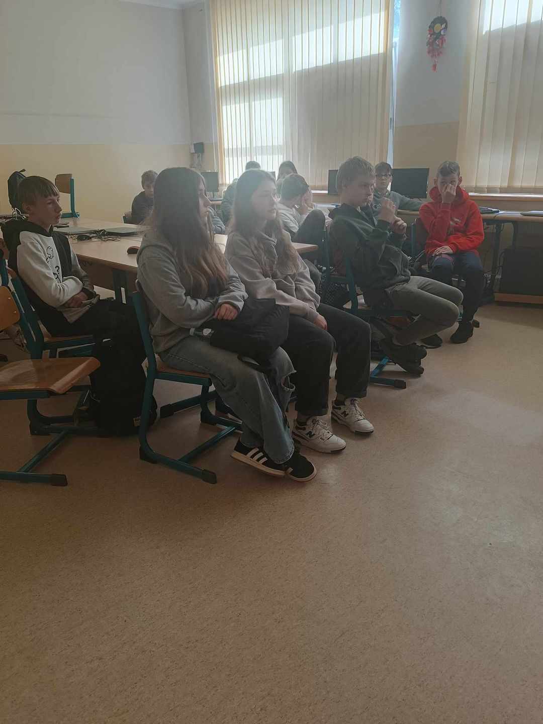 Grupa uczniów siedząca w sali komputerowej podczas zajęć