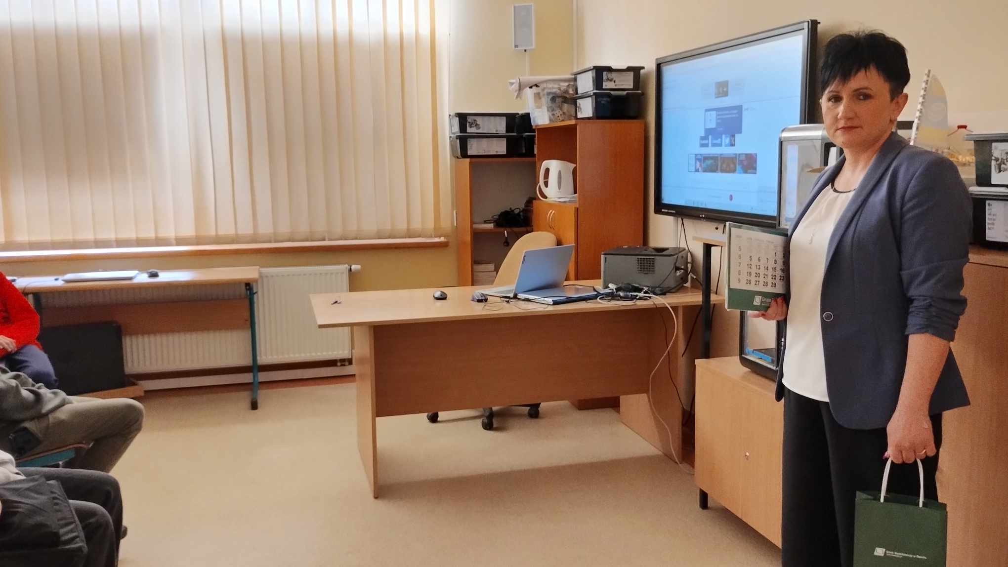 Kobieta w klasie z uczniami przy tablicy interaktywnej