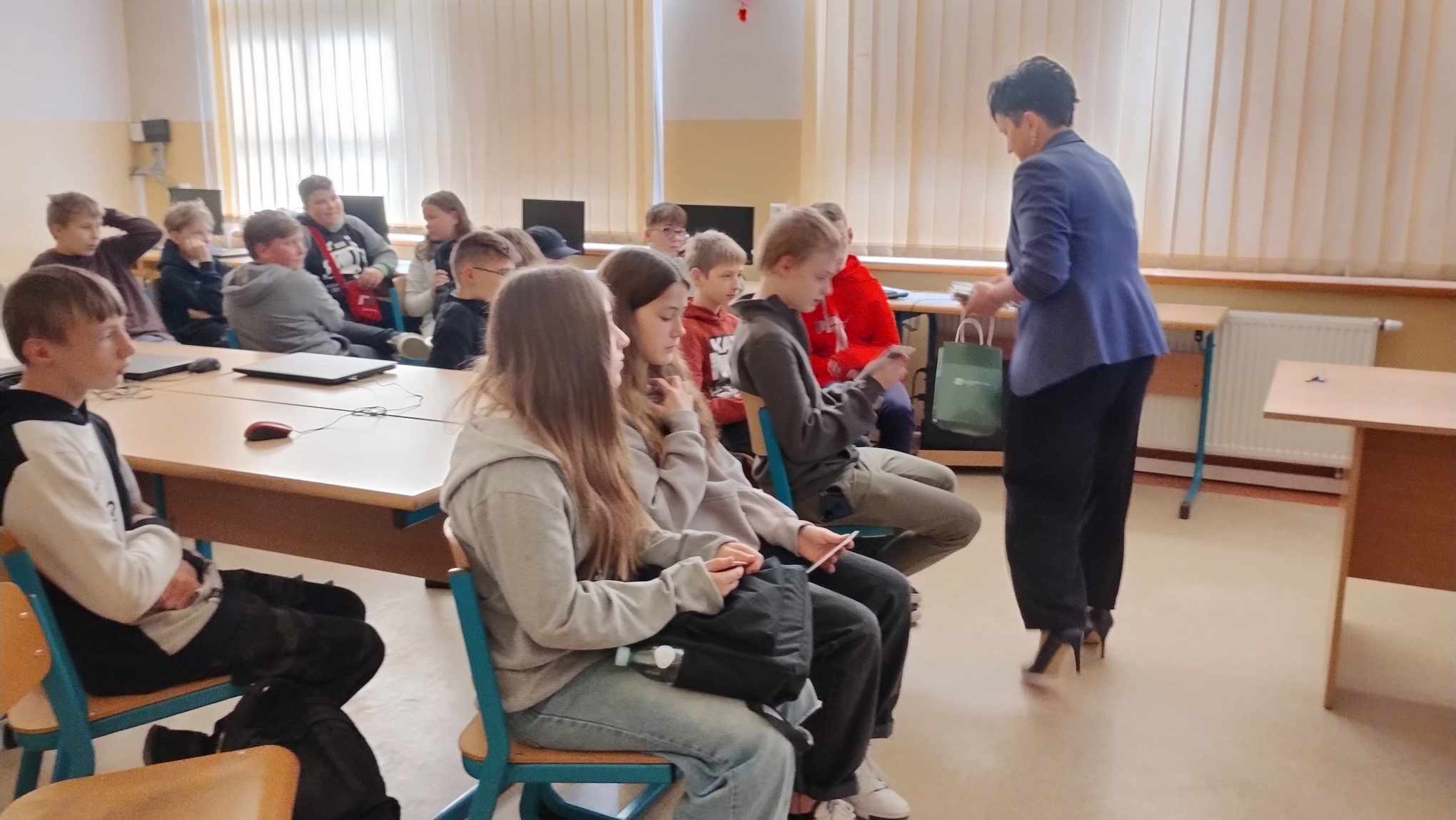 Kobieta rozdaje materiały uczniom podczas zajęć w klasie